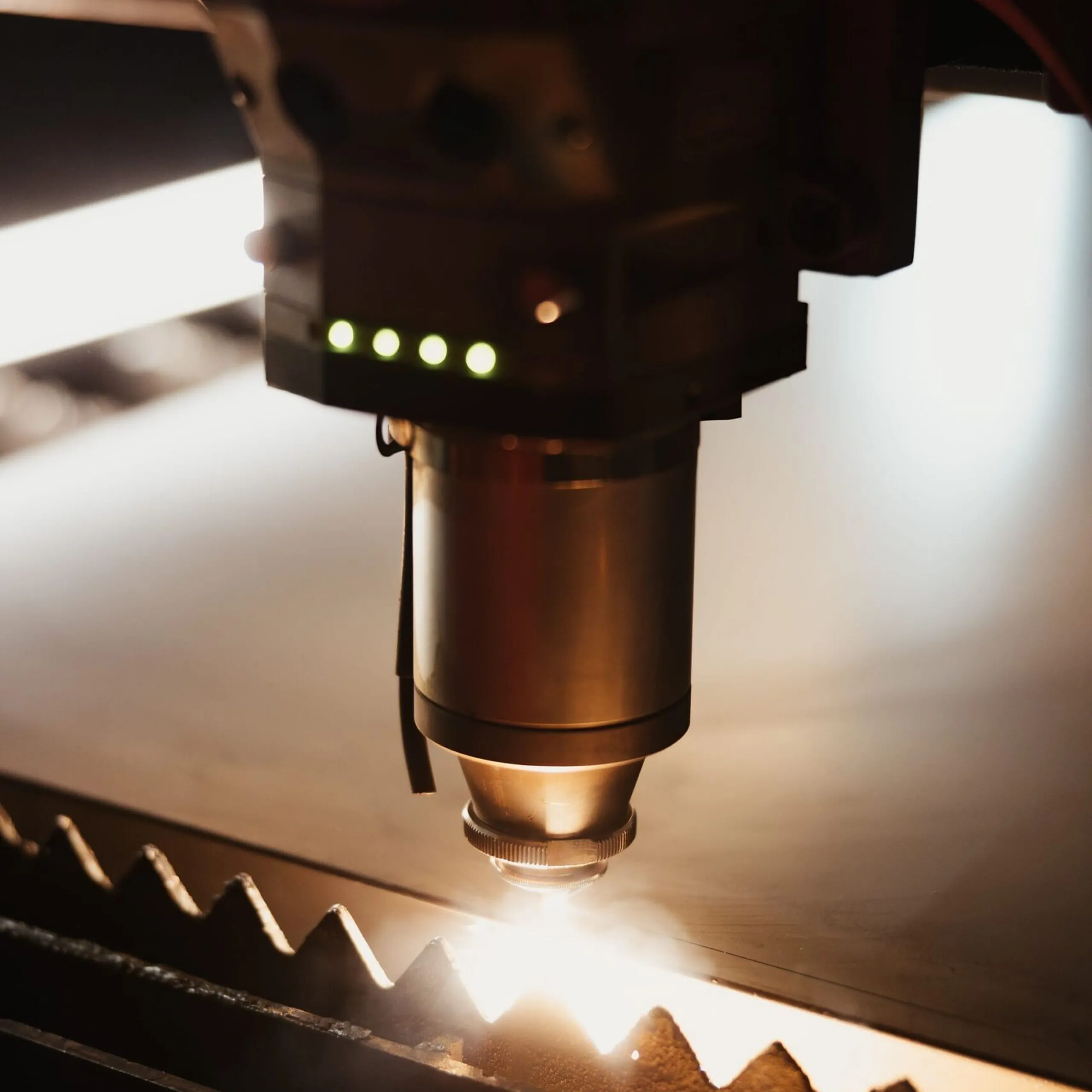 Nahaufnahme eines Schneidkopfes einer Metallbearbeitungsmaschine beim Metallschneiden; Funken sprühen, warmes Licht glänzt auf dem Metallblech.