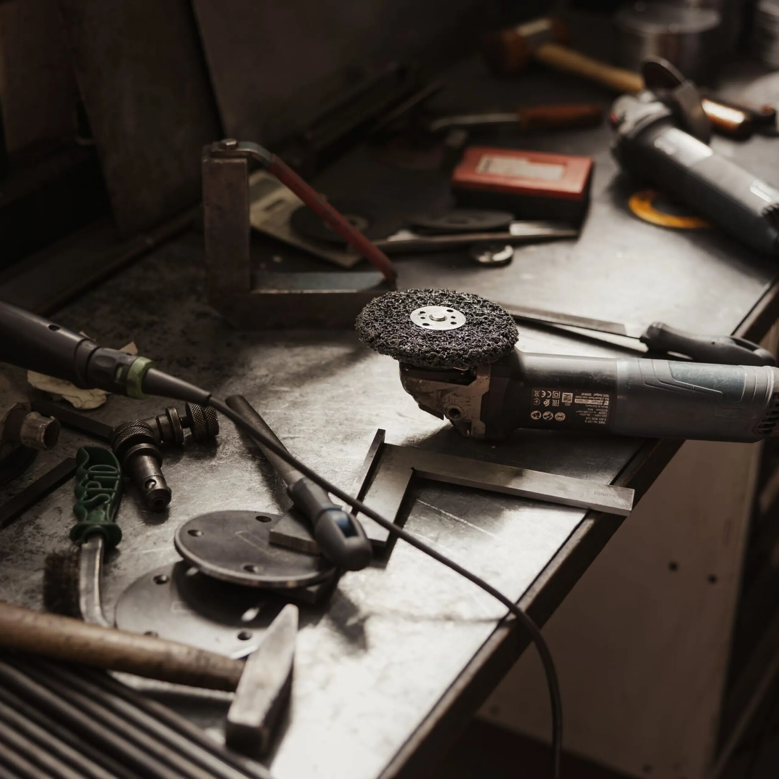 Metallbau-Werkstatt in Südtirol: Arbeitsbank mit Winkelschleifer, Schleifscheibe, Bohrer und weiterem Werkzeug.