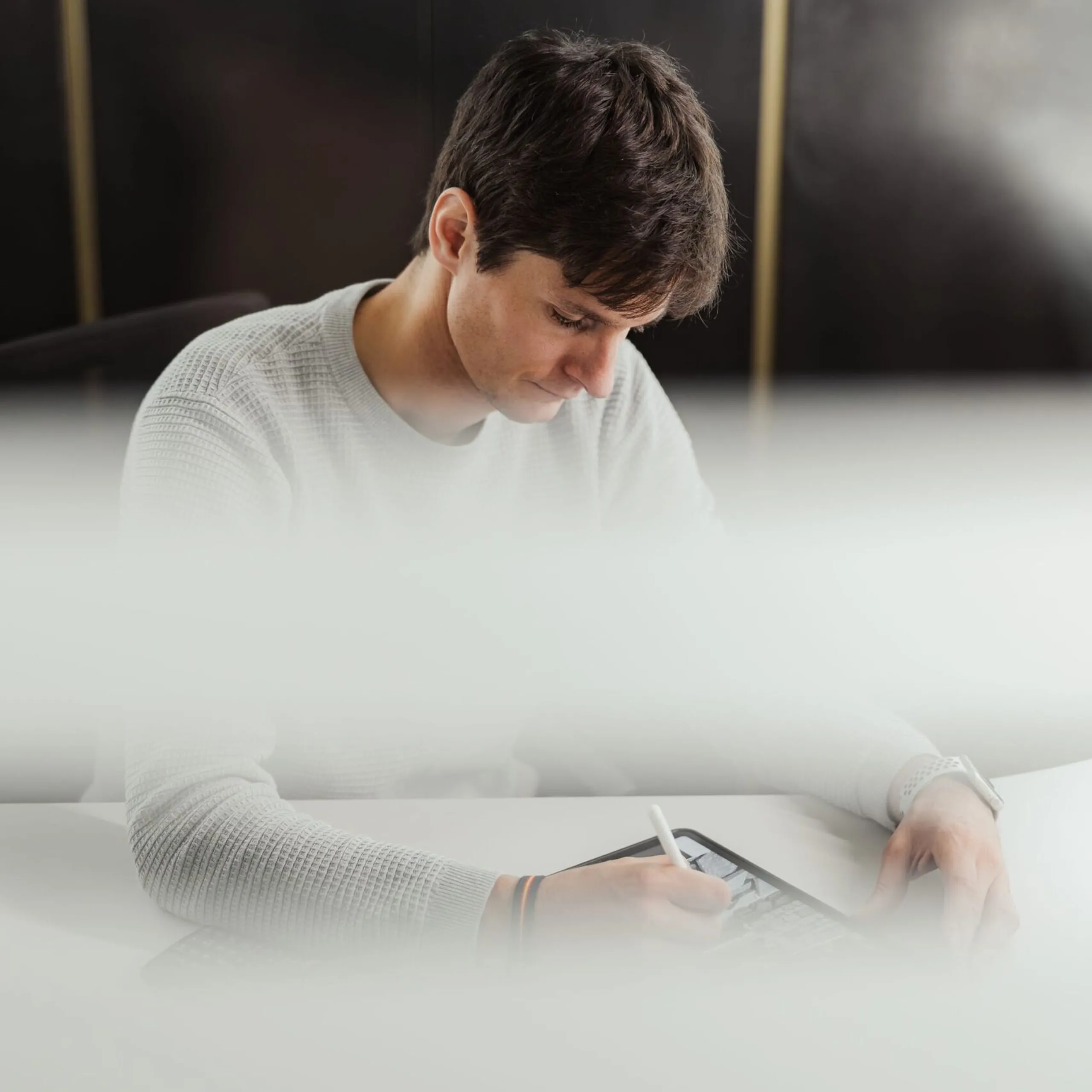 Person sitzt am Schreibtisch und verwendet einen Stylus auf einem Tablet, in einem Büro einer Metallbaufirma in Südtirol.