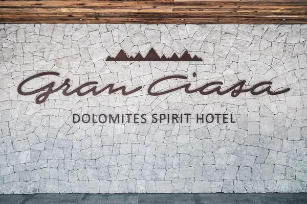 Steinwand mit dunkelbraunem, kursivem Schriftzug und Bergsilhouette; darunter Dolomites Spirit Hotel.