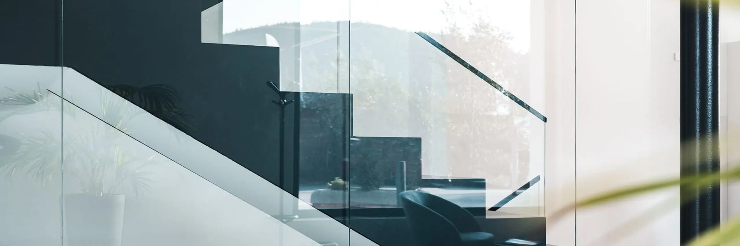 Moderne Innenansicht einer Glas- und Stahltreppe hinter Glaswänden, klare Linien, Lichtstreifen und Spiegelungen in einer Metallbaufirma in Südtirol.