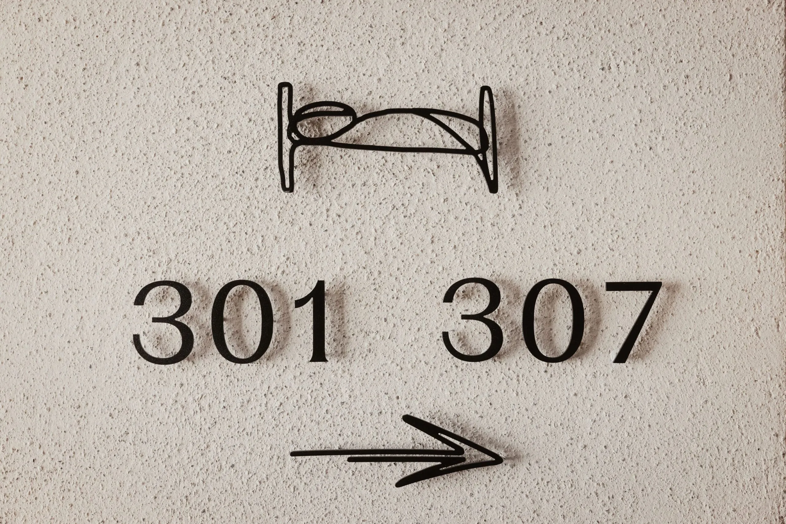 Segnaletica murale con icona di letto in ferro, numeri 301 e 307 e freccia verso destra.