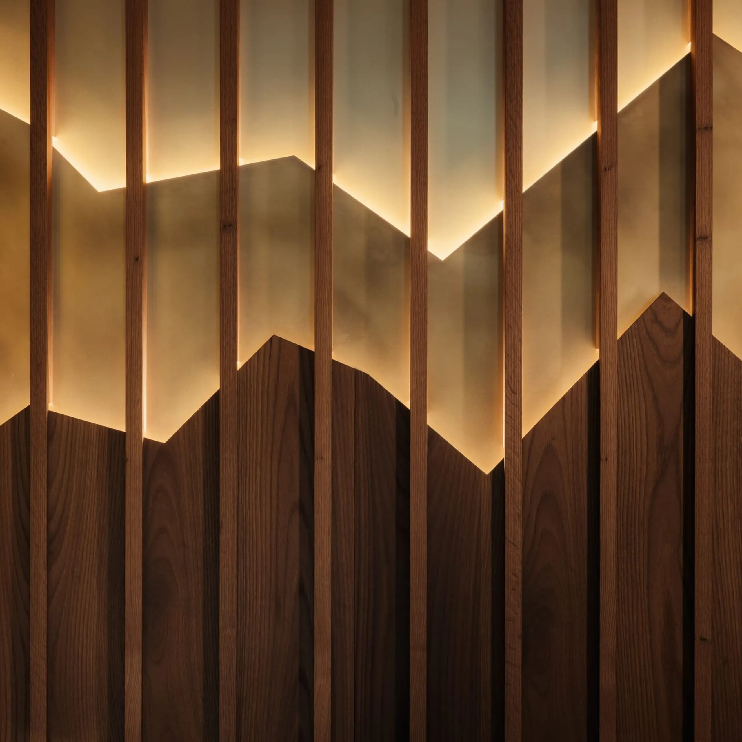 Vertikale Holzbalken vor warm beleuchtetem Hintergrund, der chevronartige Gebirgskanten bildet; unten dunkle Holzpaneele.