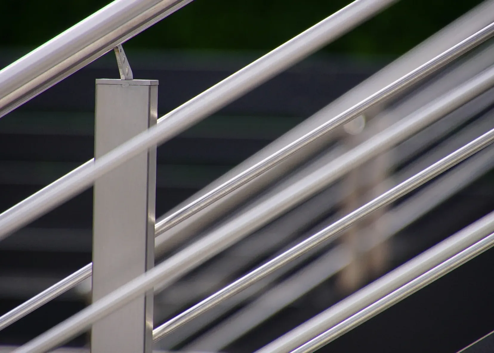 Balaustra in acciaio inox con montante verticale e cavi paralleli, primo piano, sfondo sfumato.